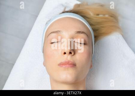 Jeune femme sain repos de peau éclatante pendant l'environnement professionnel de traitement de beauté spa. Le concept minimaliste de soins de la peau met en valeur l'hydratation bien-être Banque D'Images