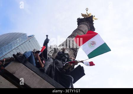 Les fans mexicains grimpent sur les statues de l'Ange de l'indépendance agitant des drapeaux pendant la célébration de la Coupe du monde. Banque D'Images
