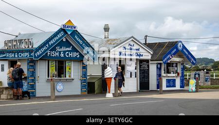 Petits kiosques en bois colorés en bord de mer vendant du poisson et des frites à emporter et de la crème glacée à un endroit côtier West Bat Dorset Banque D'Images