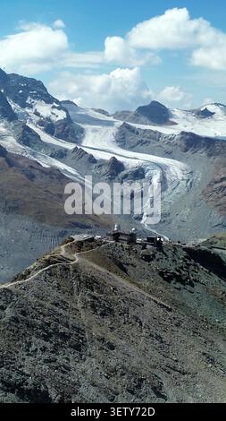 Vue aérienne de l'observatoire du Gornergrat et du complexe hôtelier situé sur une crête rocheuse avec le glacier du Gorner et les sommets enneigés à Zermatt, Valais Banque D'Images