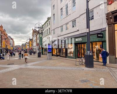 Les gens marchant le long de l'artère commerçante historique Briggate à Leeds, West Yorkshire, Angleterre, devant les devantures de magasins de détail par une journée nuageuse. Banque D'Images