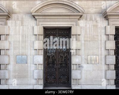 Entrée en calcaire néo-classique du Leeds Civic Hall, West Yorkshire, Angleterre avec des portes complexes en fer forgé et des plaques murales commémoratives. Banque D'Images