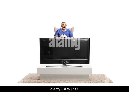 Homme senior excied assis dans un fauteuil devant la télévision et tenant un ballon de football isolé sur fond blanc Banque D'Images
