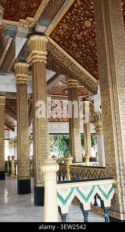 Couloir de temple intérieur à faible angle avec des rangées de hauts piliers dorés au plafond à motifs Banque D'Images