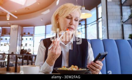 Femme d'affaires multitâche intelligemment. Femme professionnelle mange et messages simultanément. Femme professionnelle dans les affaires porter multitâches pendant elle Banque D'Images