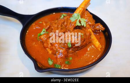 Authentique agneau Rogan Josh servi dans une poêle noire. Ce plat Cachemire classique présente de tendres jarrets de mouton ou d'agneau cuits lentement dans un riche et épicé a rouge Banque D'Images