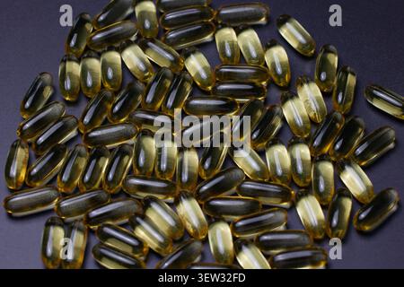 Capsules d'huile de poisson d'or Omega 3 sur fond noir. Capsules naturelles en gros plan avec vitamine E, A. Banque D'Images