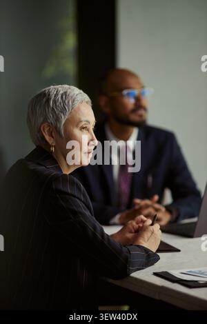 Plan vertical d'une femme d'affaires principale dirigeant l'industrie pétrolière en réunion avec un collègue masculin, examinant la stratégie et la planification des investissements. Utile pour le leadership énergétique, la prise de décision d'entreprise Banque D'Images