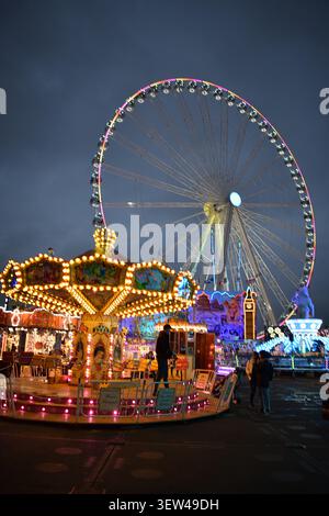 Londres, Angleterre, Royaume-Uni – 28 novembre 2019 : carrousel et roue d'observation géante illuminés à Winter Wonderland à Hyde Park après la tombée de la nuit. Banque D'Images