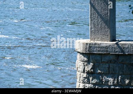 L'eau coule paisiblement autour d'un pilier de pierre, reflétant magnifiquement la lumière du soleil. Banque D'Images