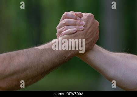 Les mains en force. Rivalité, gros plan sur la lutte au bras masculin. Hommes mesurant les forces, les bras. Deux hommes luttent au bras. Rivalité, vs, défi, force Banque D'Images