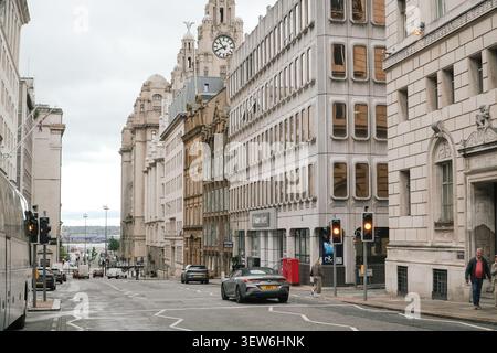 Vue sur la rue de Water Street, Liverpool, avec une architecture patrimoniale et le Royal Liver Building au loin. Banque D'Images