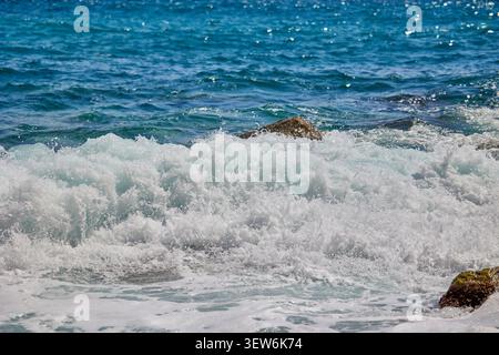 Vagues vagues se brisant contre les rochers sur les rives de la mer Méditerranée pendant la journée. Plage de Cala del Moraig à Benitachell d'Alicante, Espagne. Banque D'Images