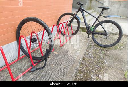 Vélo volé dans le parking des vélos de l'école secondaire. Roue restante visible et verrouillée. Banque D'Images