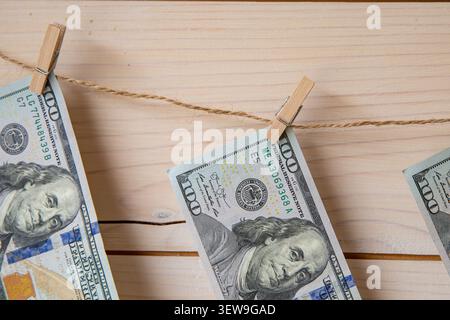 Billets de banque en dollars AMÉRICAINS accrochés sur corde à linge avec pinces à linge sur fond en bois Banque D'Images