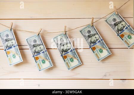 Billets de banque en dollars AMÉRICAINS accrochés sur corde à linge avec pinces à linge sur fond en bois Banque D'Images