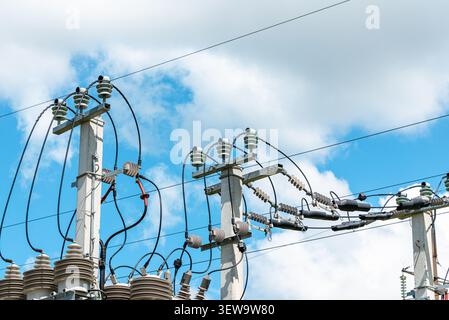 Gros plan des isolateurs électriques et des lignes électriques sur des poteaux électriques en béton. Équipement de distribution de réseau électrique et poteaux électriques contre un ciel bleu. Banque D'Images