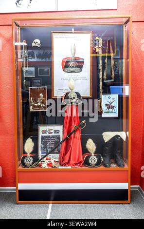 Samara, Russie - 16 avril 2026 : uniformes militaires, sabres, chapeaux de Hussars noirs russes exposés dans une vitrine en verre au Musée le 5ème Hussard A. Banque D'Images