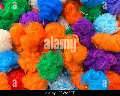 Assortiment coloré de poufs éponge de bain multicolores en maille empilés ensemble dans un marché Banque D'Images