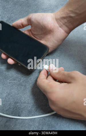 Une personne connecte son téléphone à l'aide d'un câble de charge Banque D'Images