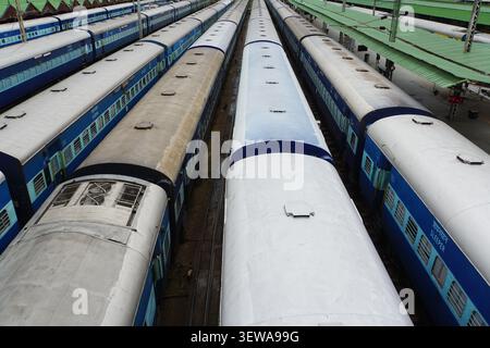 Une vue de dessus montre plusieurs longs trains de voyageurs bleus et blancs des chemins de fer indiens stationnés côte à côte sur les voies d'une gare ferroviaire. Les trains fe Banque D'Images