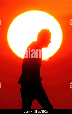 Île de Palms, États-Unis. 26 juin 2026. Un homme âgé marche devant le soleil levant qui silhouette son corps alors qu'il marche le long de la plage sur Wild Dunes, 26 juin 2026 à Isle of Palms, Caroline du Sud. Crédit : Richard Ellis/Richard Ellis/Alamy Live News Banque D'Images