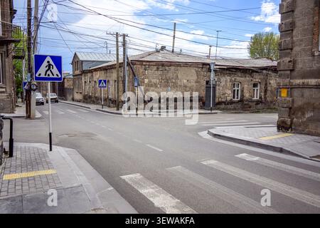 Coin de rue avec panneau de passage pour piétons. De vieux bâtiments en pierre bordent la route tranquille Banque D'Images