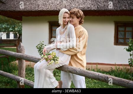 Jeune couple profite d'un moment tendre à l'extérieur dans une tenue boho chic, rayonnant d'amour Banque D'Images