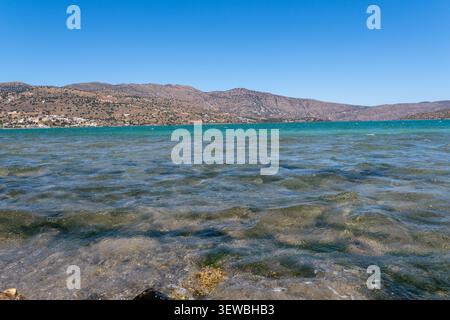 Paysage marin pittoresque d'une baie méditerranéenne en Crète avec des eaux turquoises transparentes ondulantes près du rivage, des montagnes rocheuses sèches sous un ciel bleu clair, Banque D'Images