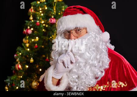 Portrait en gros plan du Père Noël demandant le silence, avec le doigt sur ses lèvres. Silence et concept secret. Banque D'Images