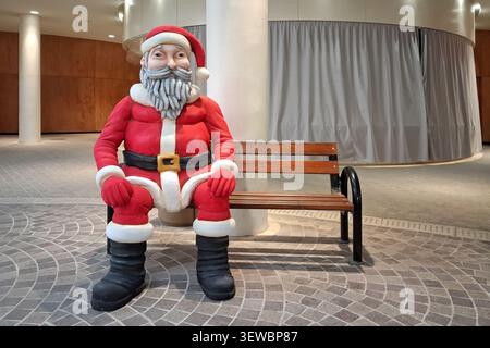 Statue du Père Noël assis sur un banc. Banque D'Images