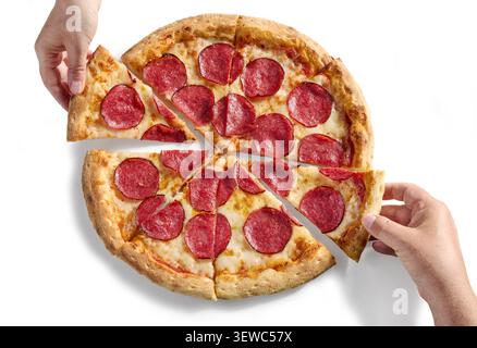 Gros plan de la main d'une personne tirant une délicieuse tranche d'une pizza au salami pepperoni entière fraîchement cuite. Proprement isolé sur un fond blanc pur. Banque D'Images