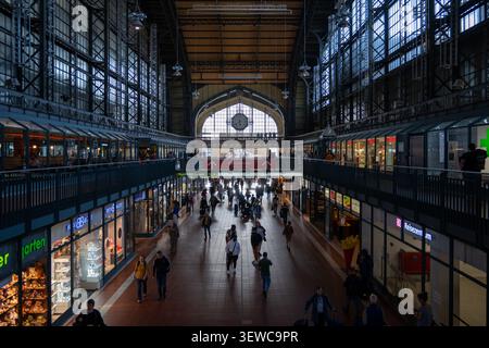 Hambourg, Allemagne - 4 avril 25 : vue sur le hall de la gare centrale de Hambourg avec une grande horloge, des magasins et des piétons à Hambourg, Allemagne. Banque D'Images