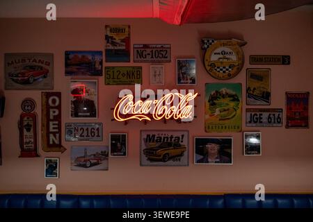 Hambourg, Allemagne - 4 avril 25 : exposition murale intérieure avec une enseigne au néon Coca-Cola et des plaques de voyage vintage au Miniatur Wunderland à Hambourg, en Allemagne. Banque D'Images