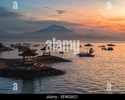 Vue aérienne de la plage de Sanur au lever du soleil avec des bateaux traditionnels, des belvédères en pierre, et le mont Agung en arrière-plan, Kecamatan Denpasar Selatan, Bali, Indo Banque D'Images