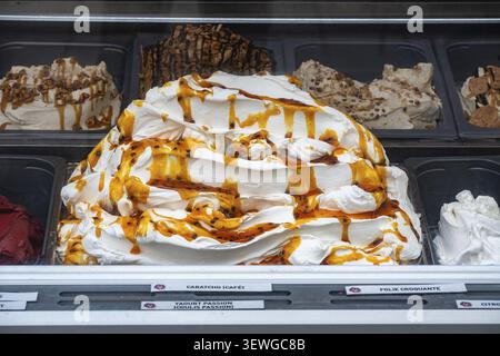 Crème glacée accumulée enrobée de sauce caramel dans une vitrine de crème glacée dans un salon de crème glacée dans la vieille ville de Saint Malo, suivie par d'autres Banque D'Images