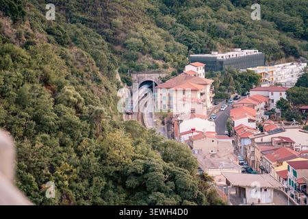 Vue en grand angle d'un train de voyageurs entrant dans un tunnel dans la ville de Scilla, Italie Banque D'Images