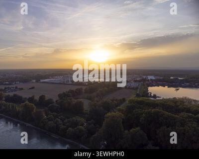 07 octobre 2022 : vue aérienne d'un complexe industriel situé le long d'une rivière au cours d'un coucher de soleil vibrant, avec de vastes champs, des arbres denses, et Banque D'Images