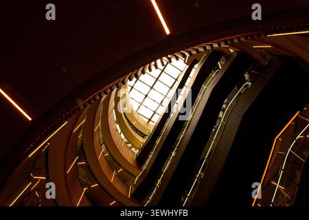 Intérieur futuriste de l'atrium avec balcons incurvés, escaliers mécaniques et toit plein-ciel en verre géométrique Banque D'Images