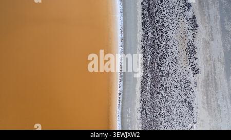 Vue aérienne du lac salé de Karlgarin montrant le contraste entre l'eau salée orange et la croûte salée blanche avec une végétation clairsemée de Karl Banque D'Images