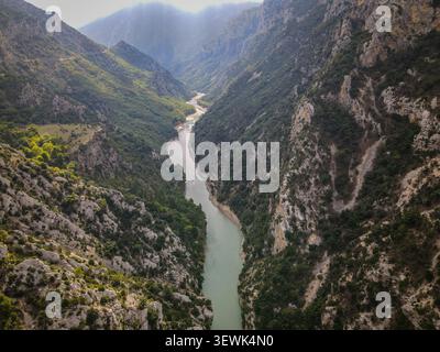 Une vue aérienne capture la magnifique gorge du Verdon, avec une rivière turquoise serpentant à travers un profond canyon. Les falaises abruptes et accidentées sont densément couvertes Banque D'Images