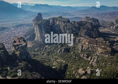 Une vue aérienne capture les formations rocheuses spectaculaires des Météores, en Grèce, avec le monastère de la Sainte Trinité perché au sommet de l'un des piliers. La ville de Banque D'Images