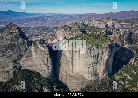Un plan large aérien capture les spectaculaires et imposants piliers rocheux des Météores, en Grèce, avec des parcelles de végétation verte sur leurs sommets plats. Dans la dista Banque D'Images