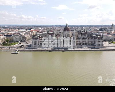 Une vue aérienne large capture le bâtiment du Parlement hongrois, un grand monument architectural, situé le long des eaux vertes boueuses du Danube Ri Banque D'Images