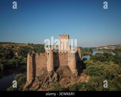 Le château d'Almourol se dresse sur une petite île dans le Tage, entouré d'arbres verts et d'eau calme sous un ciel bleu clair. Ce templar médiéval CA Banque D'Images