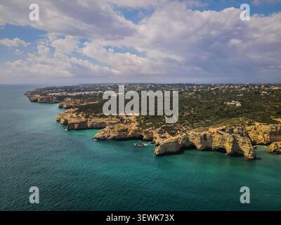 Cette vue aérienne capture la côte accidentée de l'Algarve, au Portugal, avec ses falaises dorées, ses grottes marines et ses eaux turquoises de l'Atlantique. L'image Banque D'Images