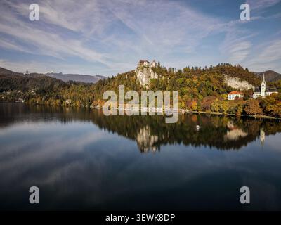 Une vue aérienne grand angle capture le lac de Bled avec le château de Bled au sommet d'une falaise sur la droite, et le clocher de l'église paroissiale Martin visible sur la droite O. Banque D'Images