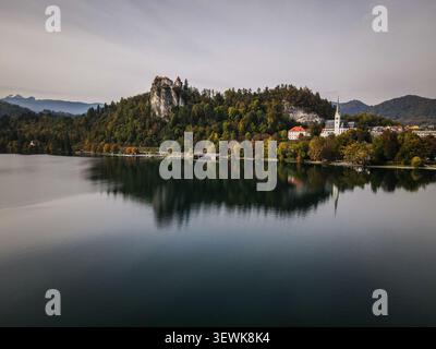Une prise de vue aérienne capture le lac de Bled, le château de Bled au sommet d'une falaise et l'église paroissiale de Martin sur la rive est, le tout reflété dans l'eau calme. Thi Banque D'Images
