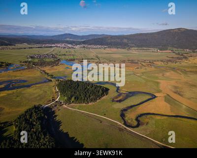 SLOVÉNIE, CERKNICA - 14 octobre 2021 : une vue aérienne montre une rivière sinueuse, des champs verts et dorés, une forêt dense et plusieurs petites villes avec Hou Banque D'Images