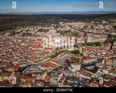 Une vue aérienne grand angle capture la ville de Plasencia, en Espagne, avec ses vastes toits de tuiles rouges, ses bâtiments urbains et ses murs médiévaux historiques A. Banque D'Images